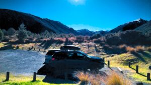 Twee (huur)auto's naast elkaar met op de achtergrond het mooi bergachtige landschap van Nieuw-Zeeland